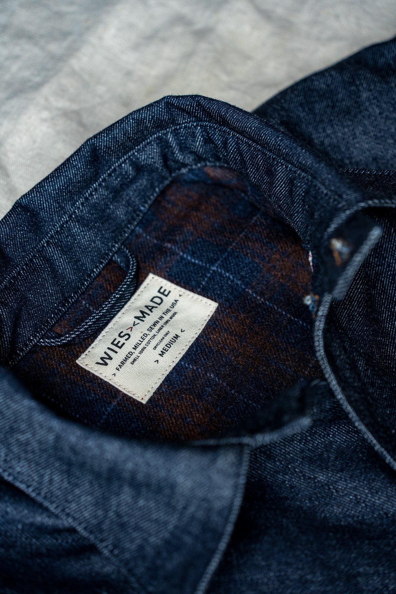 WiesMade Nico indigo denim jacket interior detail showing brand label and brown plaid collar lining.