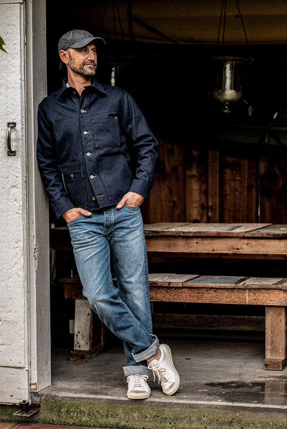 Full body shot of man in the WiesMade Nico navy denim jacket paired with faded jeans and white sneakers.