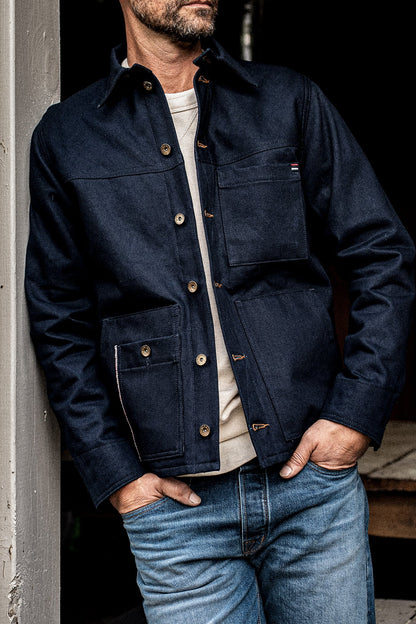 Front torso view of man wearing the WiesMade Nico navy denim jacket with brass buttons and four pockets.