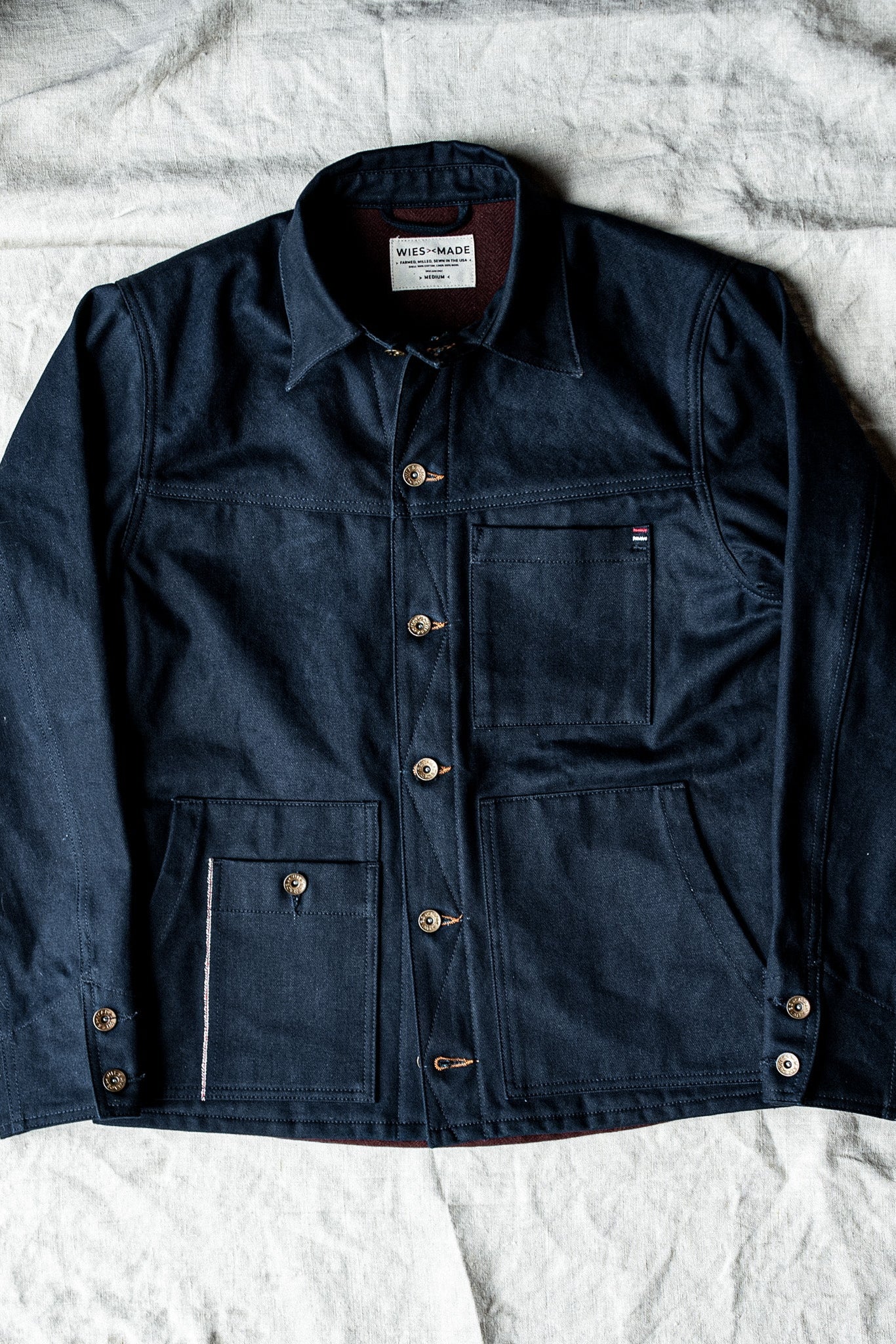 WiesMade Nico navy denim jacket full flat lay showing four-pocket design, brass buttons, and brand label.