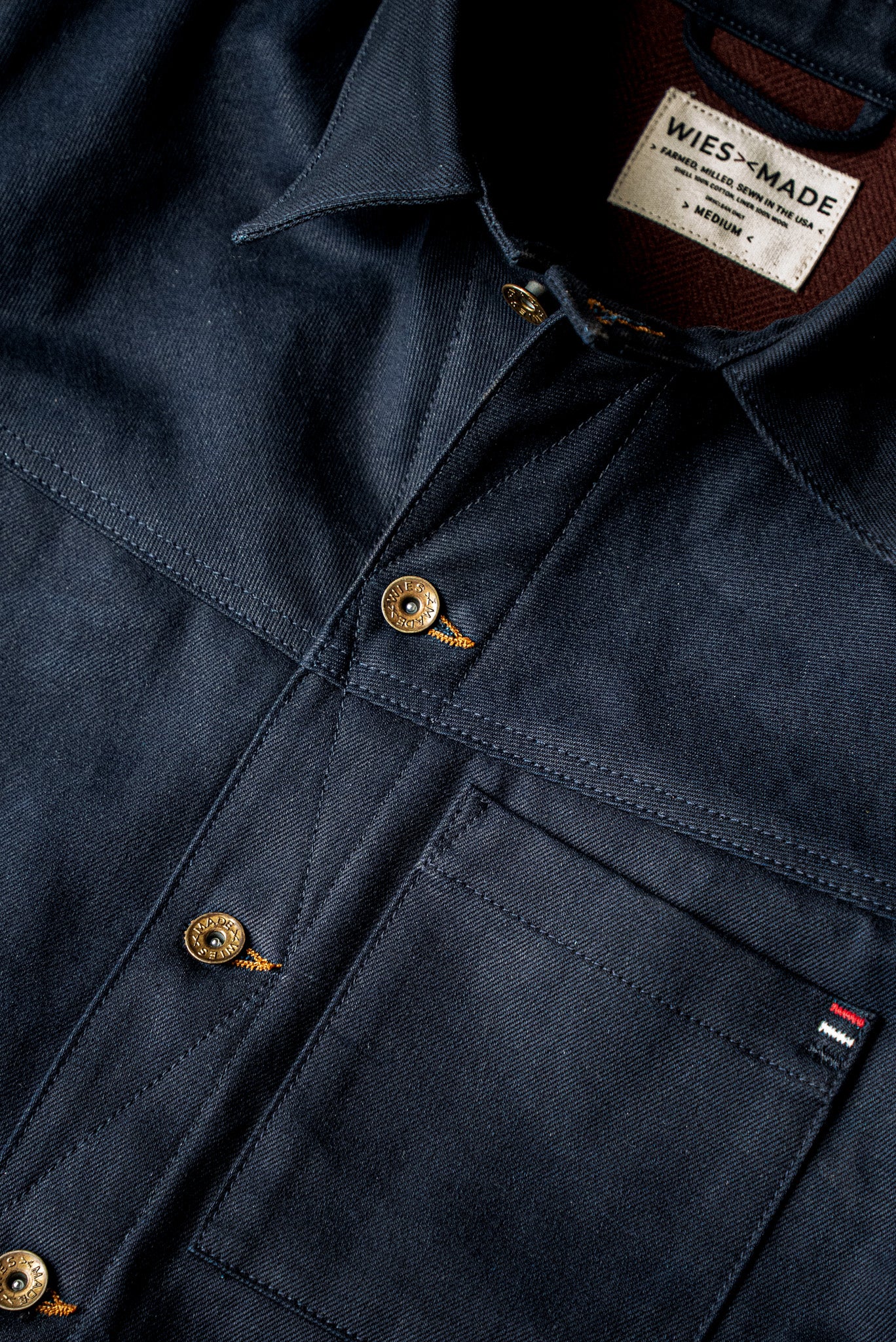 WiesMade Nico navy denim jacket flat lay showing collar, brand label, brass buttons, and patch pockets.