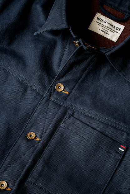 WiesMade Nico navy denim jacket flat lay showing collar, brand label, brass buttons, and patch pockets.