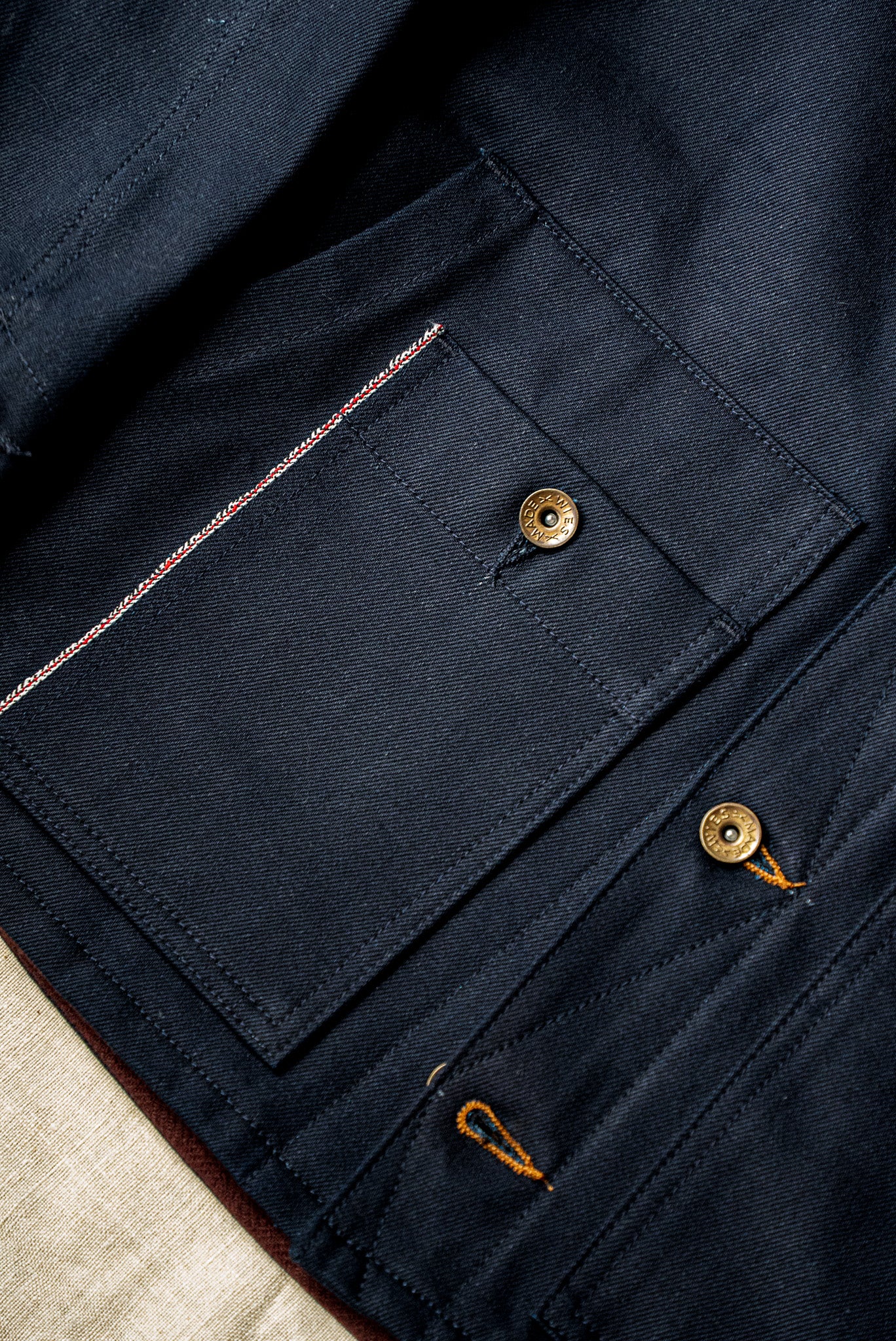 WiesMade Nico jacket in navy flat lay detail showing brass buttons, selvedge edge, and pocket construction.