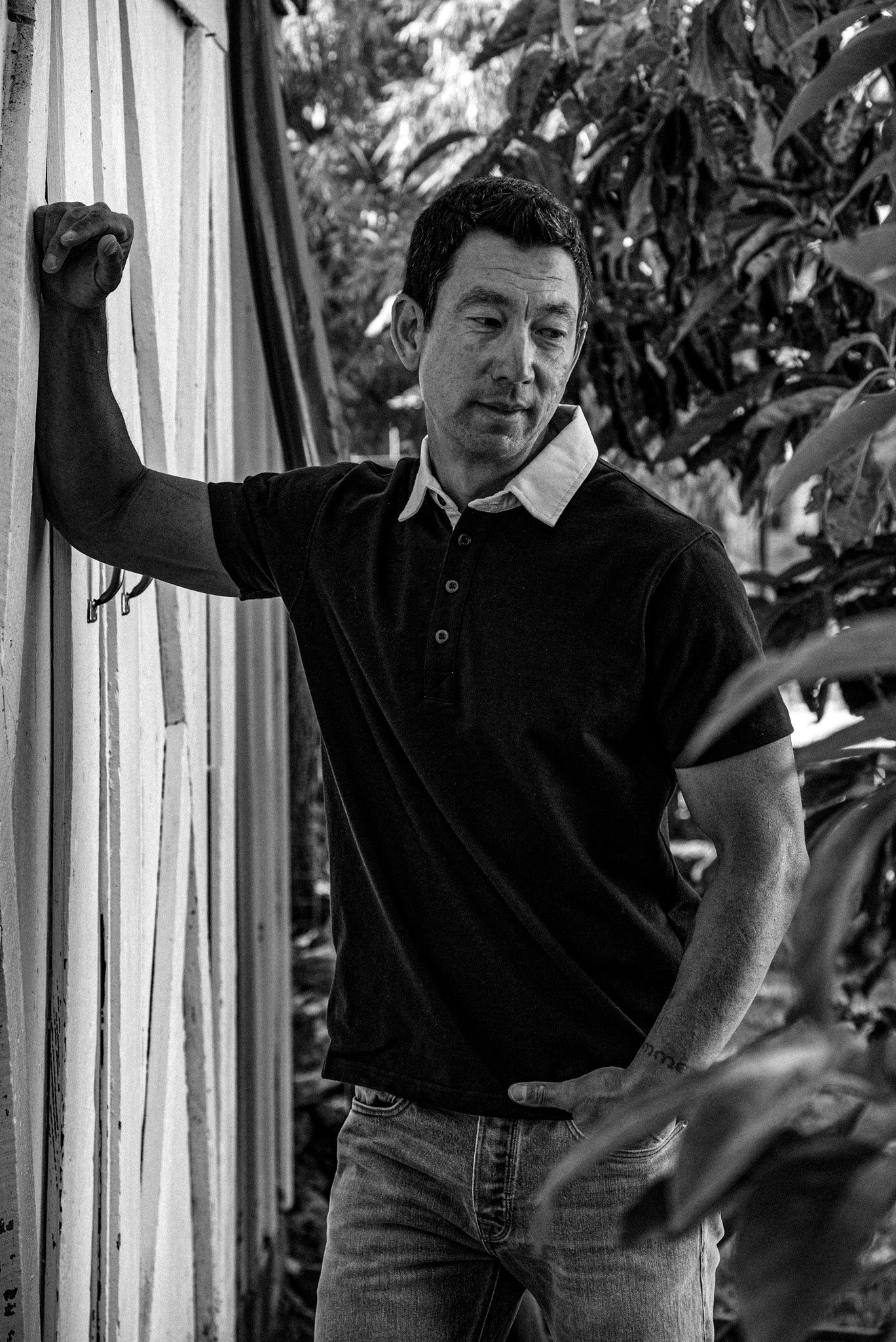 Man in short-sleeve Stinson rugby jersey with white collar and denim jeans, leaning against a weathered wall.