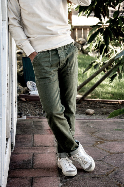 Olive military-style Scout denim pants worn with cuffed hems and white sneakers outdoors.