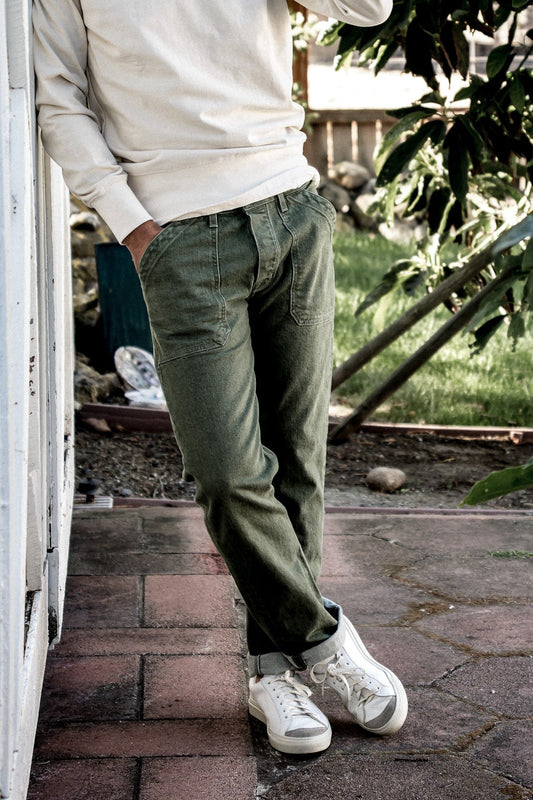 Olive military-style Scout denim pants worn with cuffed hems and white sneakers outdoors.