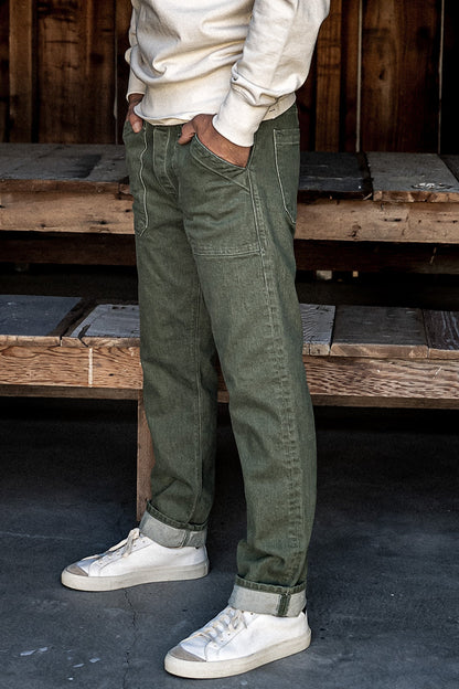 Olive Scout military denim jeans worn with cuffed hems and white sneakers.
