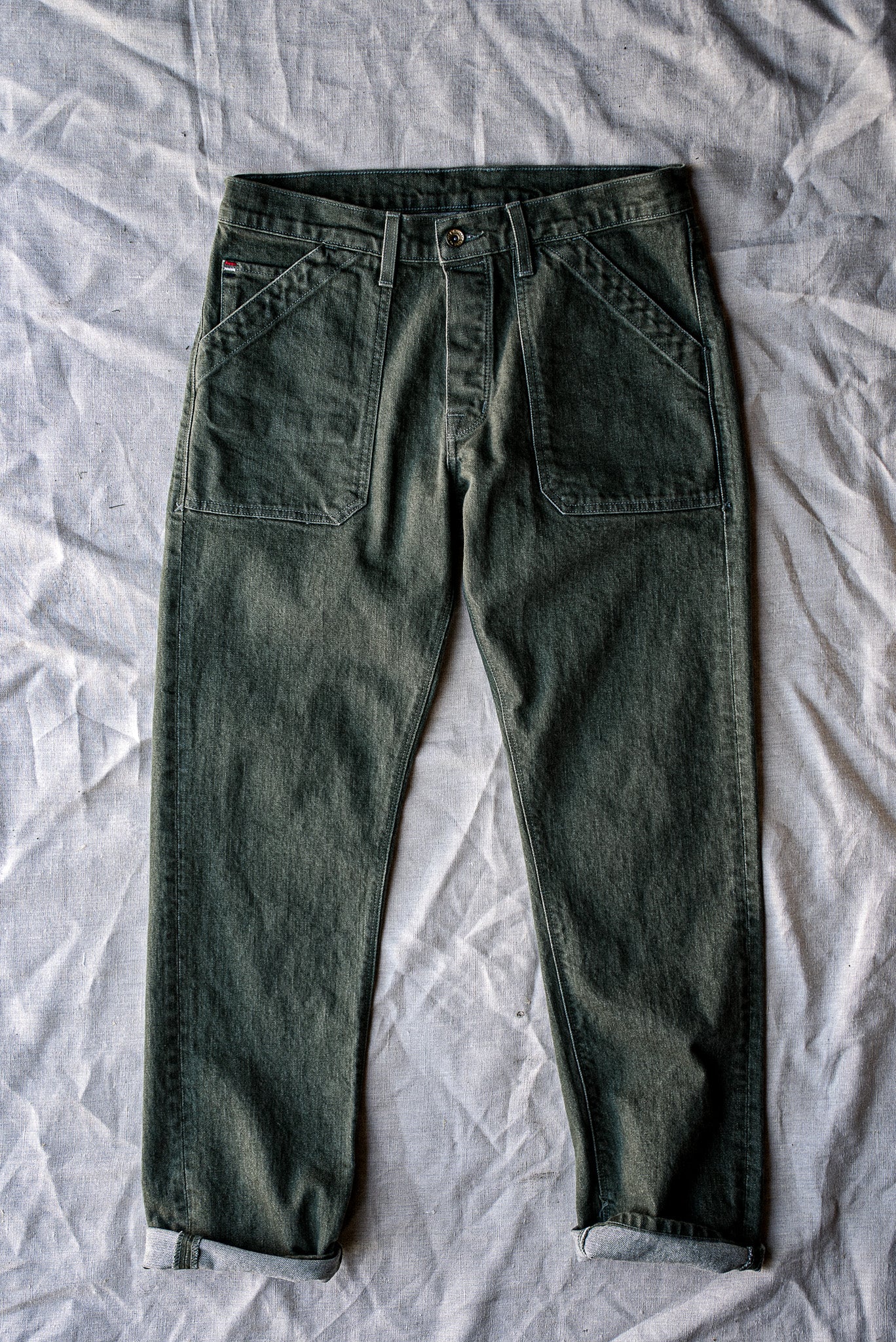Olive Scout military-style denim pant flat-laid with cuffed hems and patch pockets.