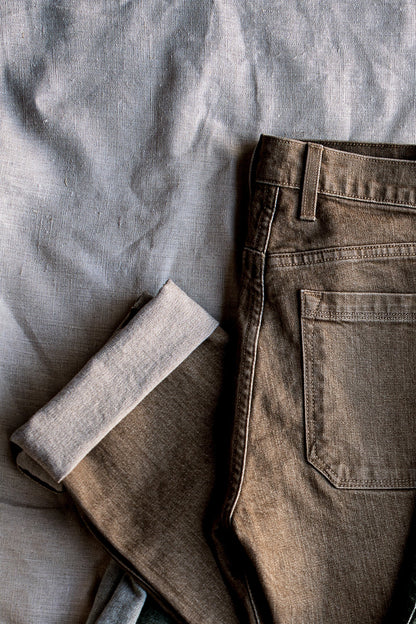 Wheat Scout broken twill denim jeans laid flat, showing back pocket and cuffed hem detail.