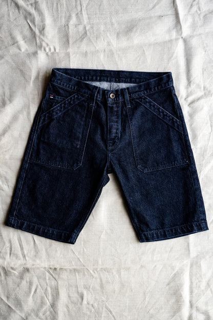 Dark ocean wash denim military shorts with patch pockets, laid flat on natural linen.