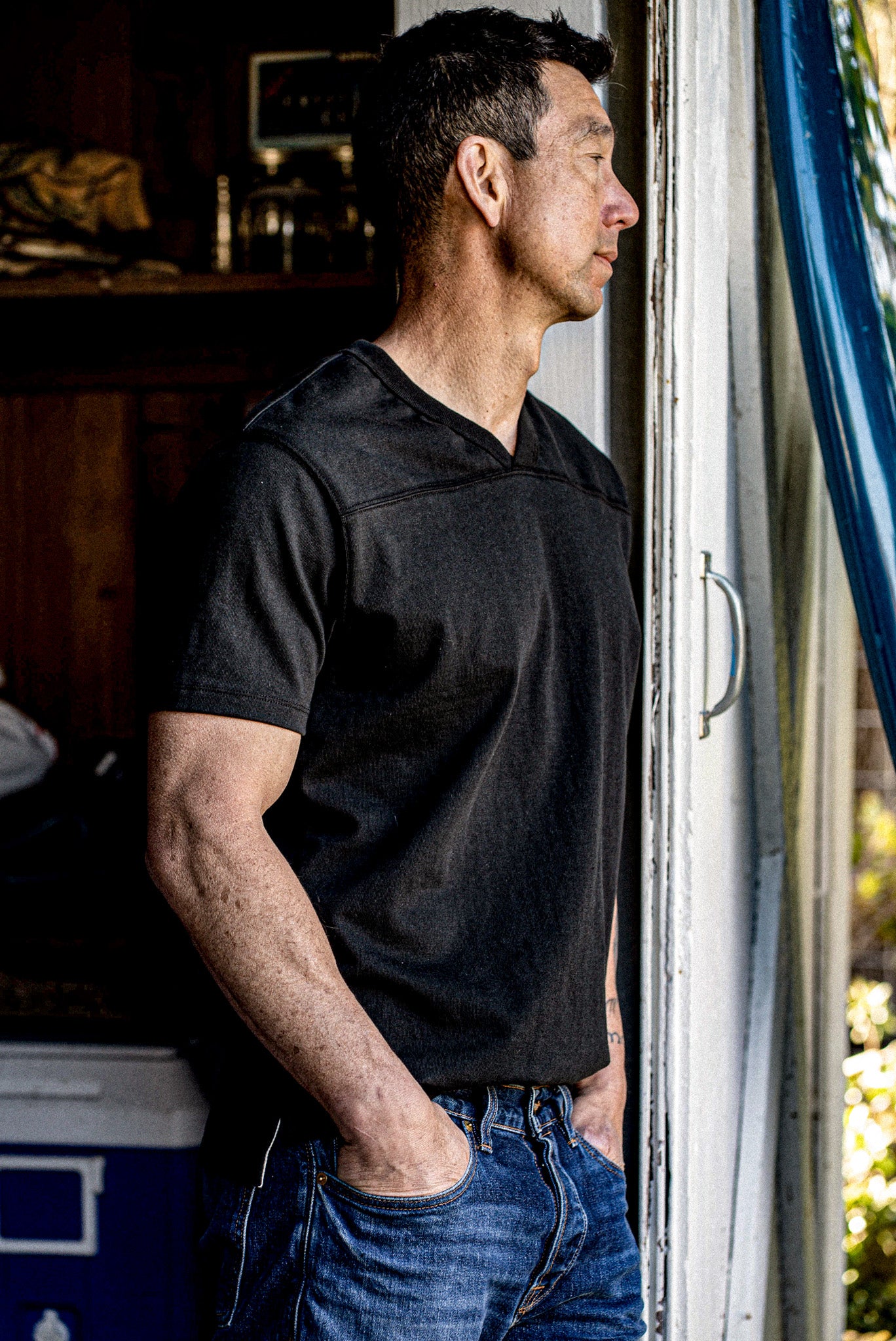 Man in Basalt black 12oz cotton V-neck jersey with yoke seam, worn with denim.