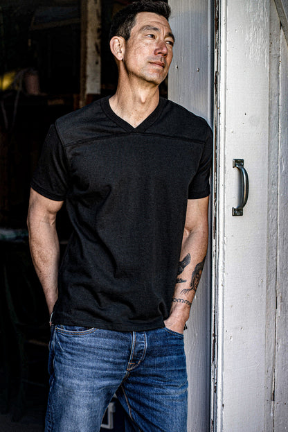 Man in Basalt Stinson V-neck cotton jersey leaning against a weathered painted door.