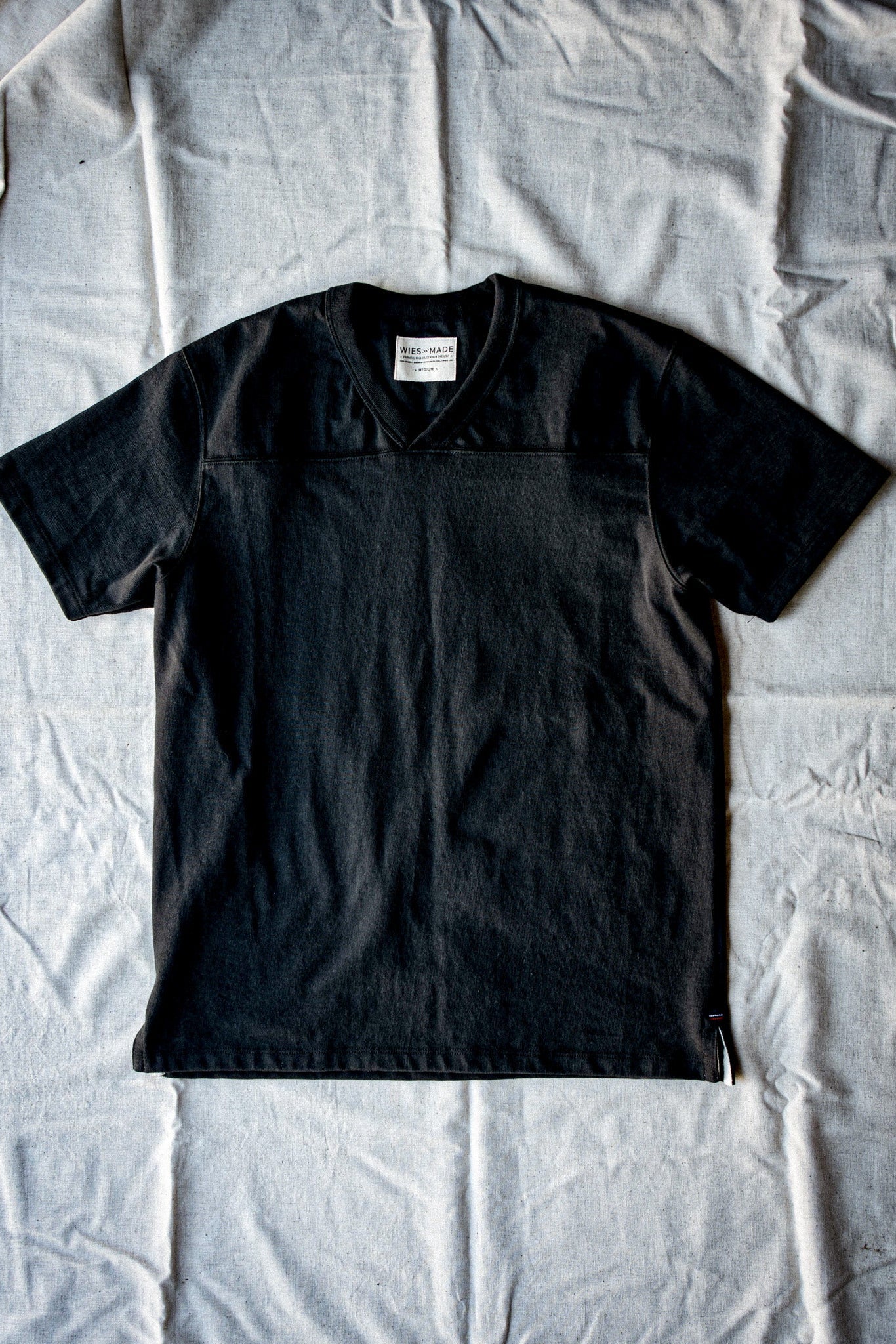Basalt 12oz cotton V-neck jersey tee laid flat on a linen backdrop.