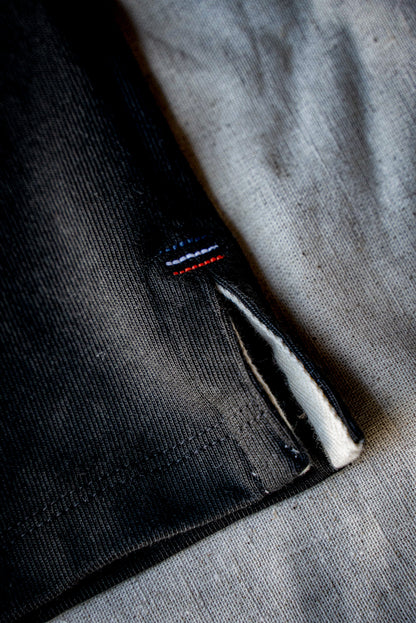 Side vent of a basalt 12oz cotton jersey with twill lining and colored bartack stitching.