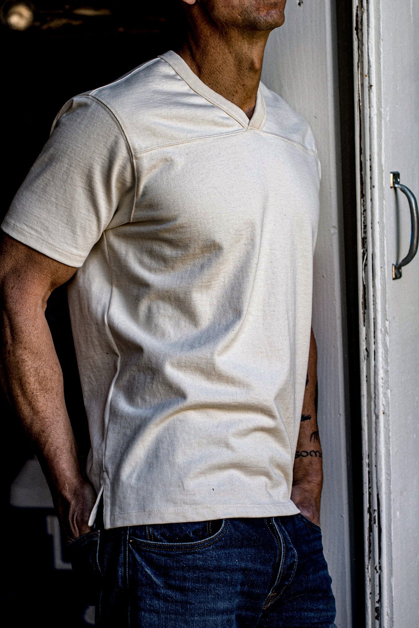 Side view of natural cotton Stinson V-neck jersey worn with dark denim jeans.