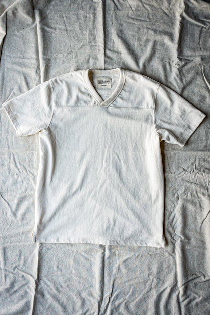 Men's natural 12oz cotton V-neck jersey tee laid flat on canvas backdrop.