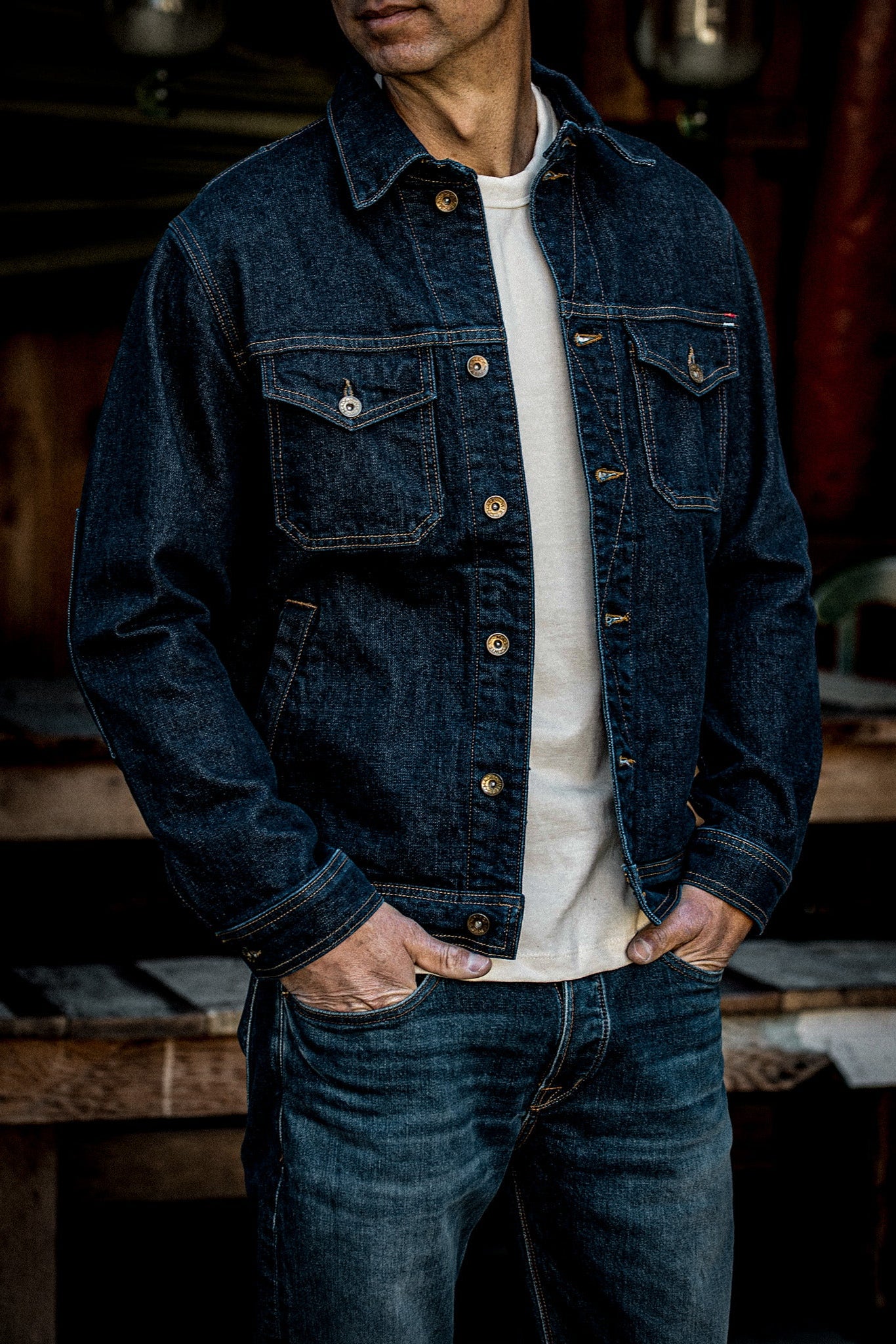 Man wearing the Artcher broken twill denim jacket in ocean blue over a cream tee, hands in jean pockets.