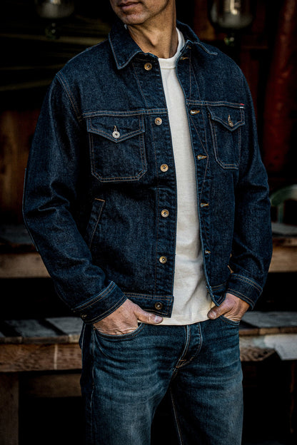 Man wearing the Artcher broken twill denim jacket in ocean blue over a cream tee, hands in jean pockets.