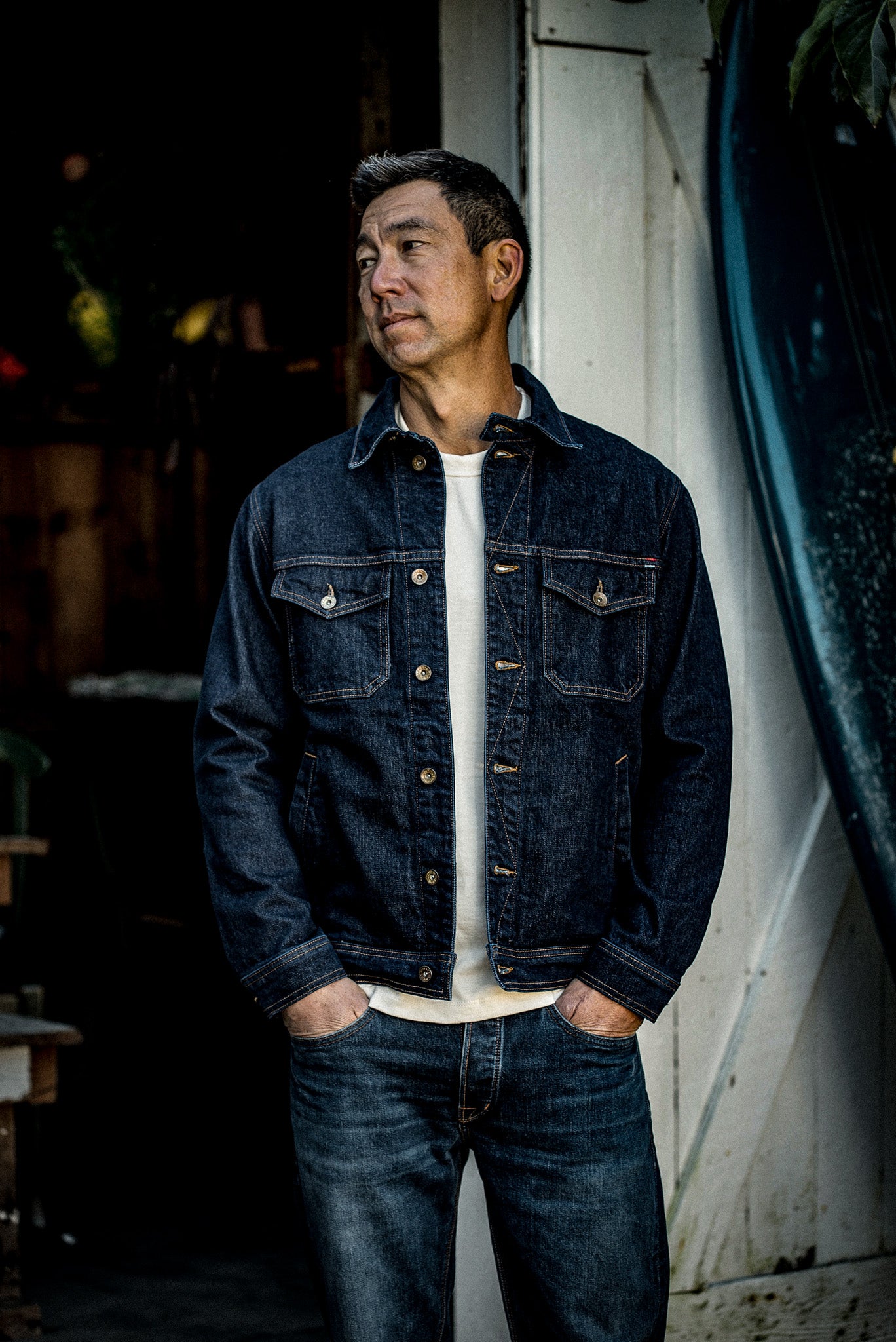 Man wearing the Artcher ocean broken twill denim jacket over a white tee, hands in pockets.