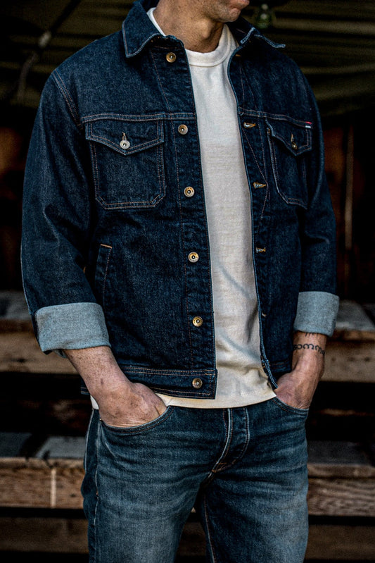 Man wearing an Ocean broken twill denim jacket with rolled cuffs over a cream tee and jeans.