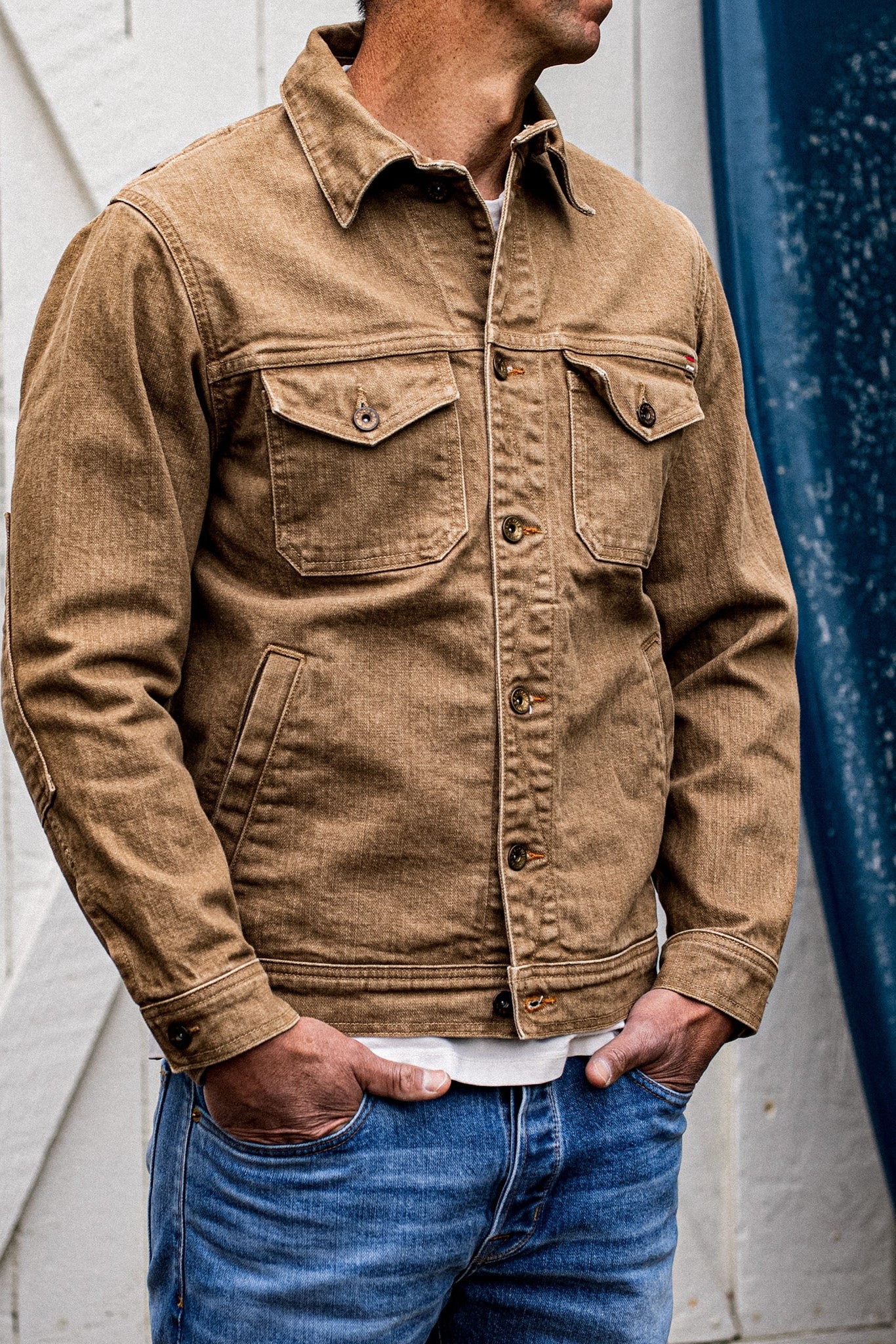 Wheat broken twill denim jacket worn open over a white tee with blue jeans.