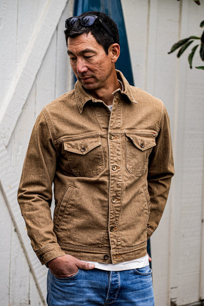 Man wearing wheat Artcher broken twill denim jacket with chest pockets over blue jeans.