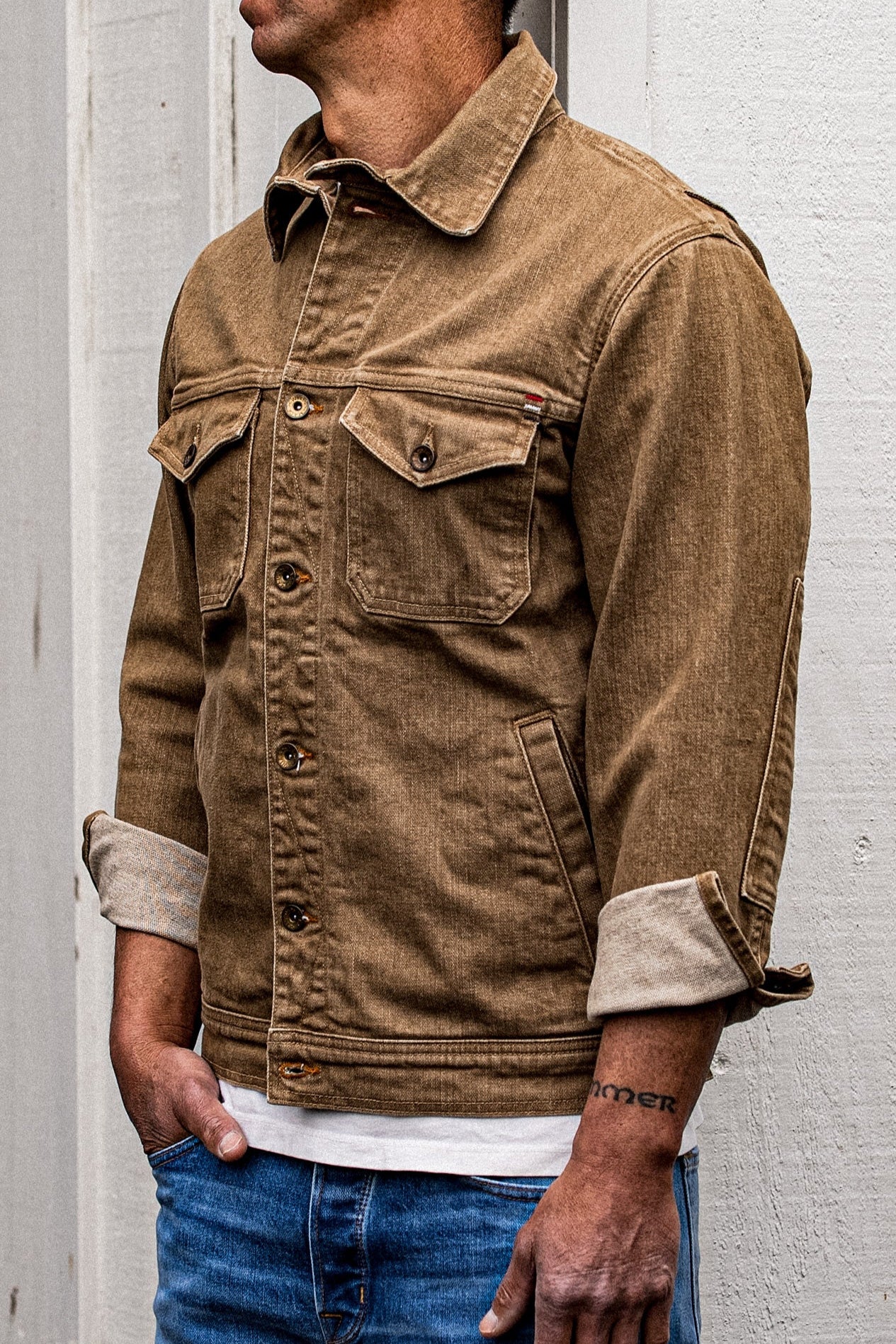 Wheat broken twill denim Artcher jacket worn on-model, side view with cuffs rolled.