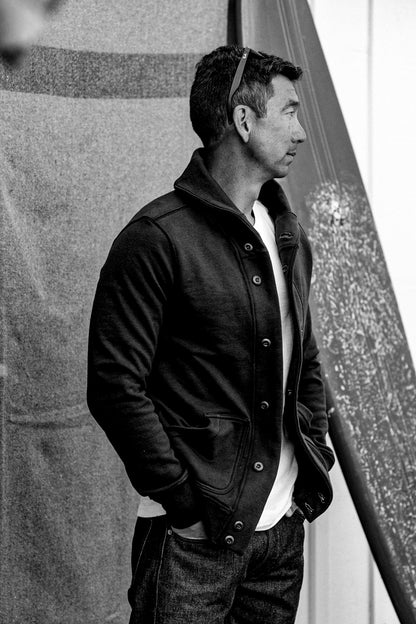 Men's Bodega shawl cardigan in basalt French terry worn buttoned over a white tee with selvedge denim jeans.