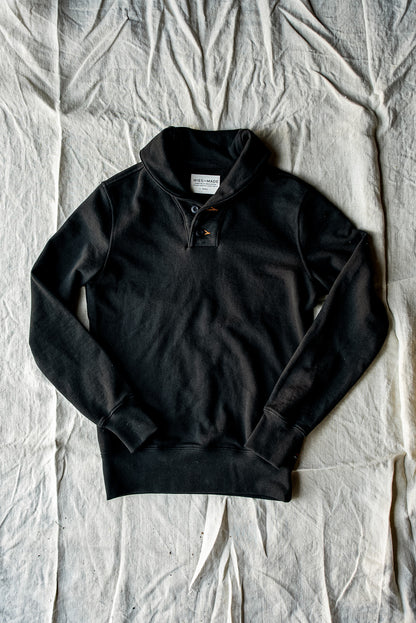Basalt black shawl collar pullover in heavyweight French terry cotton, laid flat on canvas.
