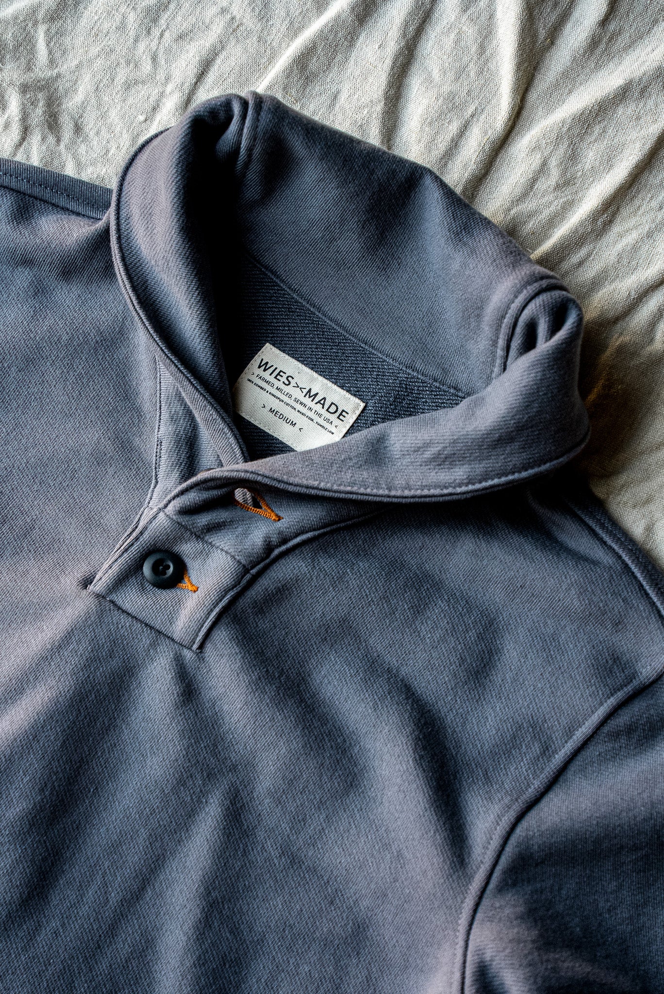 Pebble grey French terry shawl collar pullover, close-up of collar, dark button, and WiesMade label.