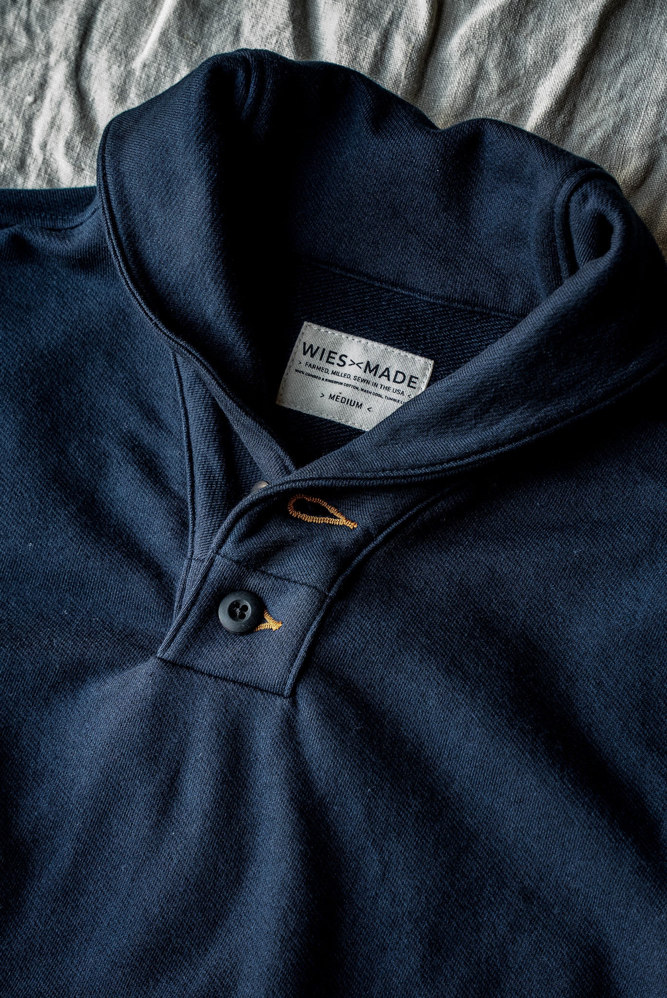Navy Bodega shawl collar pullover close-up showing button placket, contrast stitching, and French terry knit.