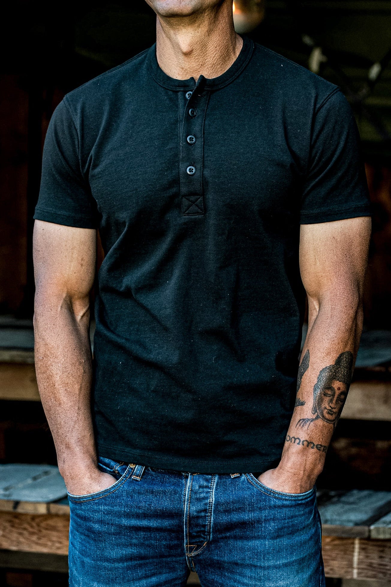 Man wearing a black short-sleeve Bolinas heavyweight henley with four-button placket, paired with blue denim jeans.
