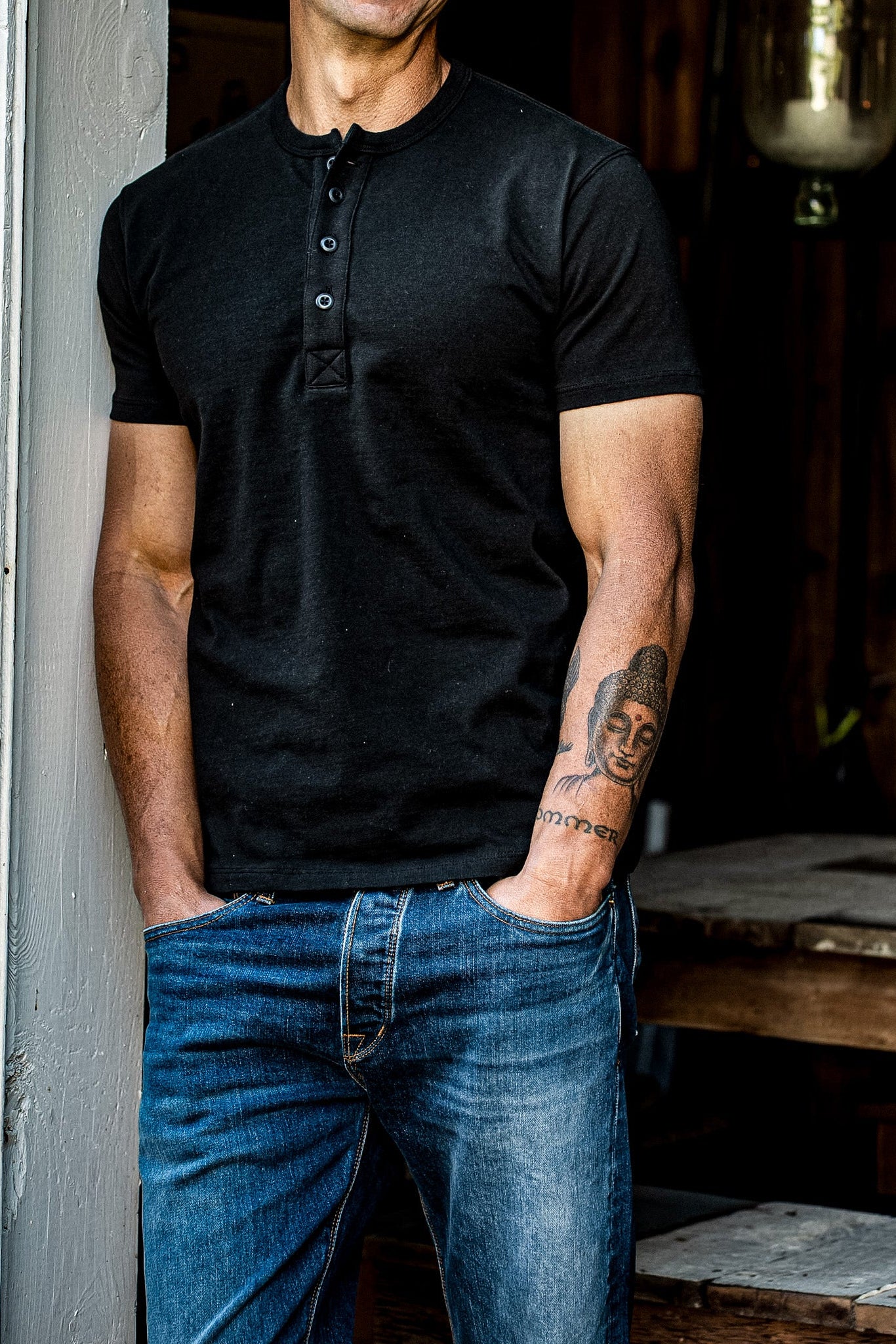 Model wearing the Bolinas four-button short-sleeve Henley in black basalt with blue selvedge denim jeans.