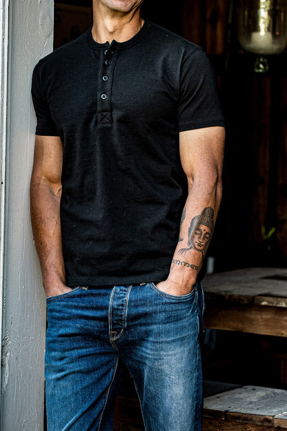 Model wearing the Bolinas four-button short-sleeve Henley in black basalt with blue selvedge denim jeans.