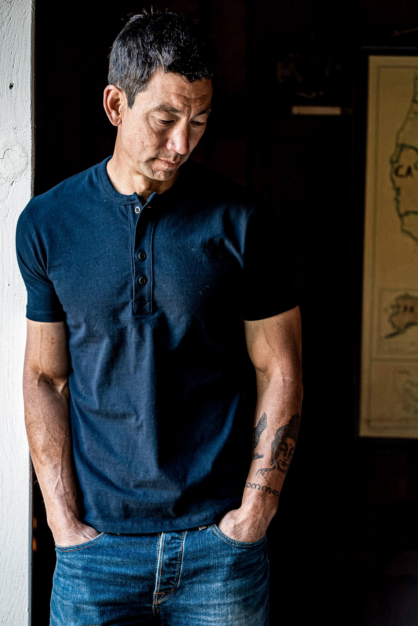 Man wearing a navy short-sleeve Bolinas Henley with four-button placket, paired with blue jeans.