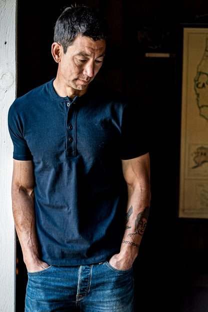 Man wearing a navy short-sleeve Bolinas Henley with four-button placket, paired with blue jeans.