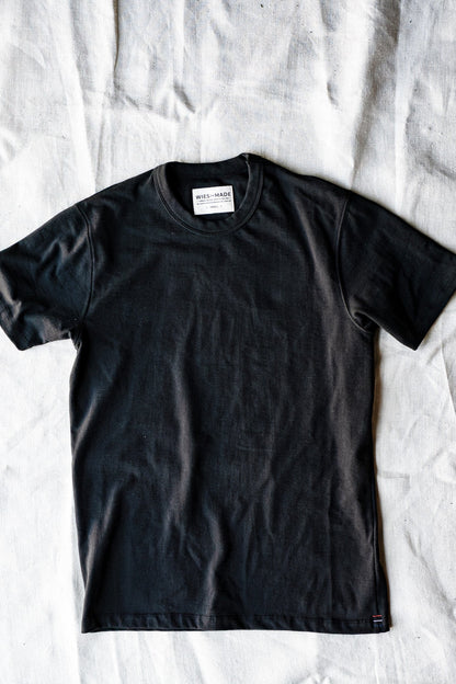 Basalt black heavyweight cotton crewneck tee laid flat on a natural linen backdrop.