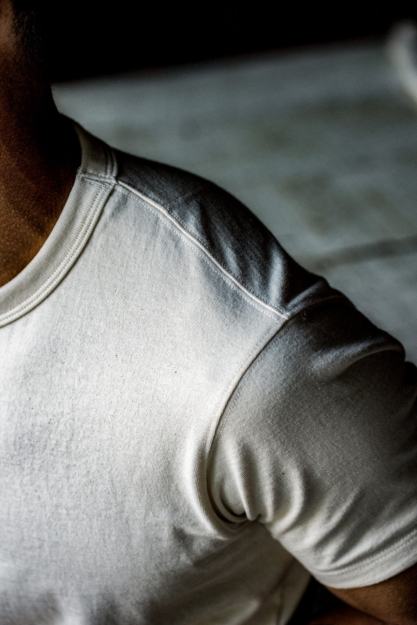 Close-up of the crew neck and shoulder seam on a natural cotton heavyweight tee.