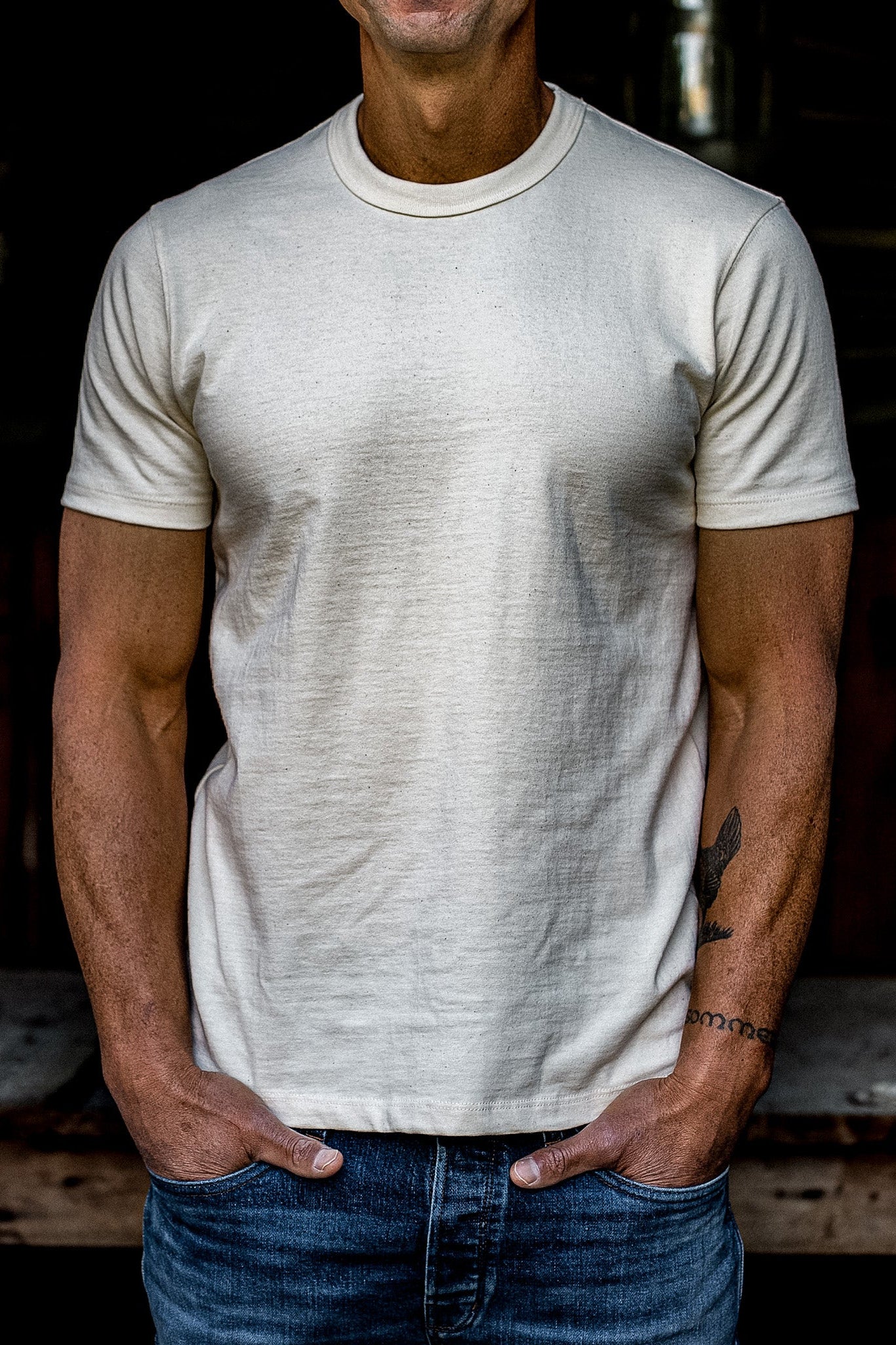 Man wearing a natural undyed heavyweight cotton crewneck tee with blue denim jeans.