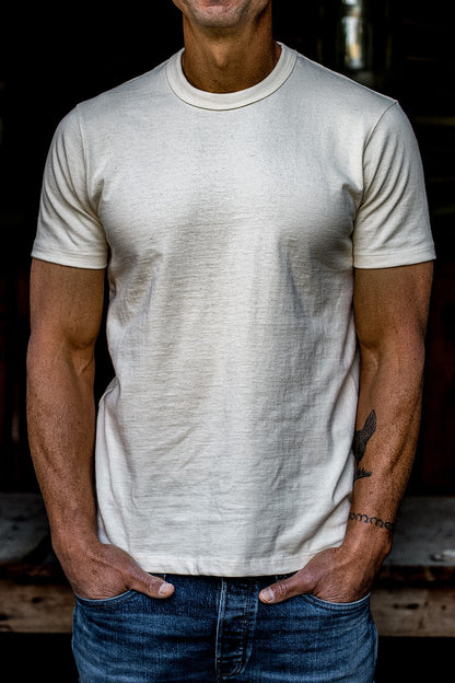 Man wearing a natural undyed heavyweight cotton crewneck tee with blue denim jeans.