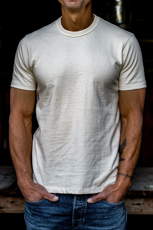 Man wearing a natural undyed heavyweight cotton crewneck tee with blue denim jeans.