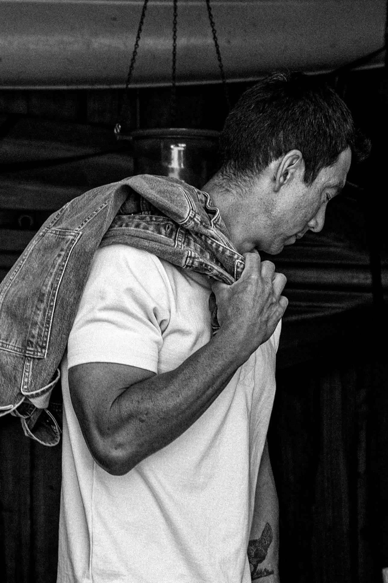 Side view of a man wearing the natural heavyweight Bolinas tee with a denim jacket slung over his shoulder.
