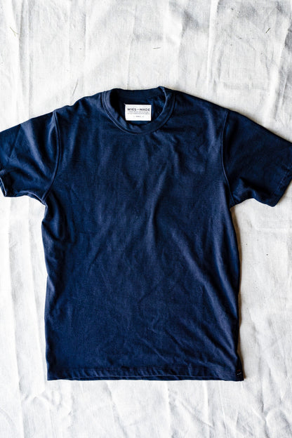 Navy heavyweight cotton Bolinas crewneck tee laid flat on a white linen backdrop.