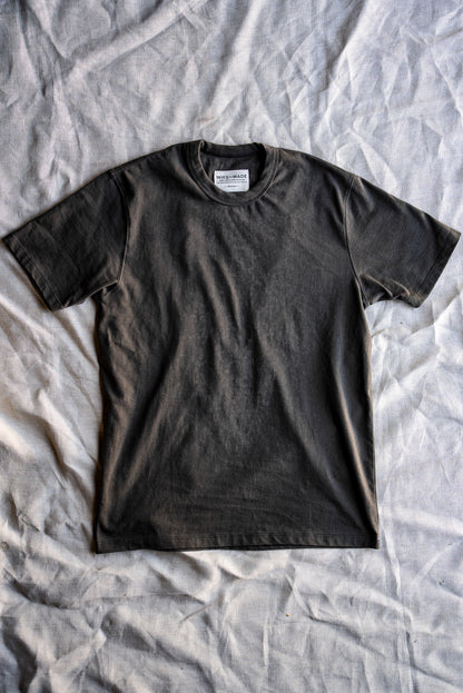Olive heavyweight cotton Bolinas tee laid flat on a crumpled linen sheet, WiesMade neck label visible.