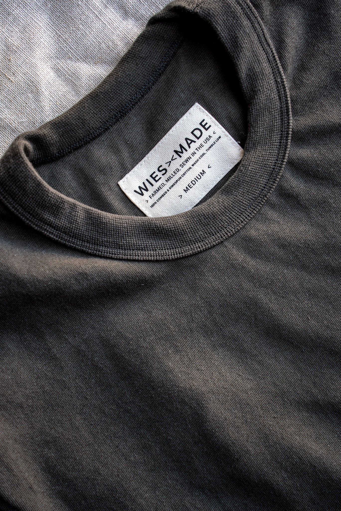 Close-up of olive Bolinas heavyweight tee collar with WiesMade USA-made cotton label.