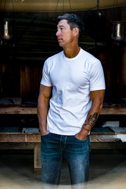 Model wears the white Bolinas heavyweight cotton tee with jeans in a rustic barn.