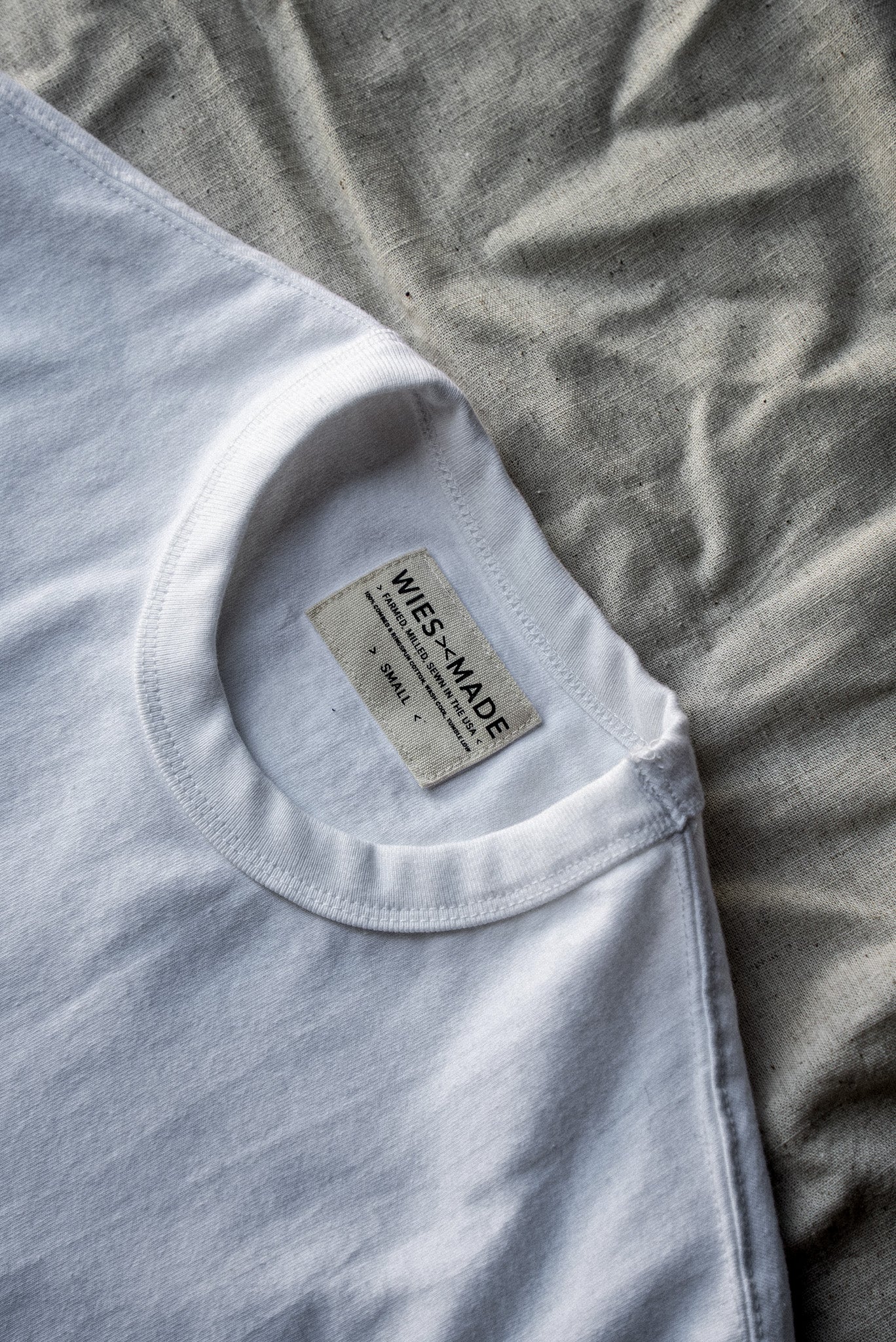 Crewneck collar of a white heavyweight cotton tee with WiesMade made-in-USA neck label, size small.