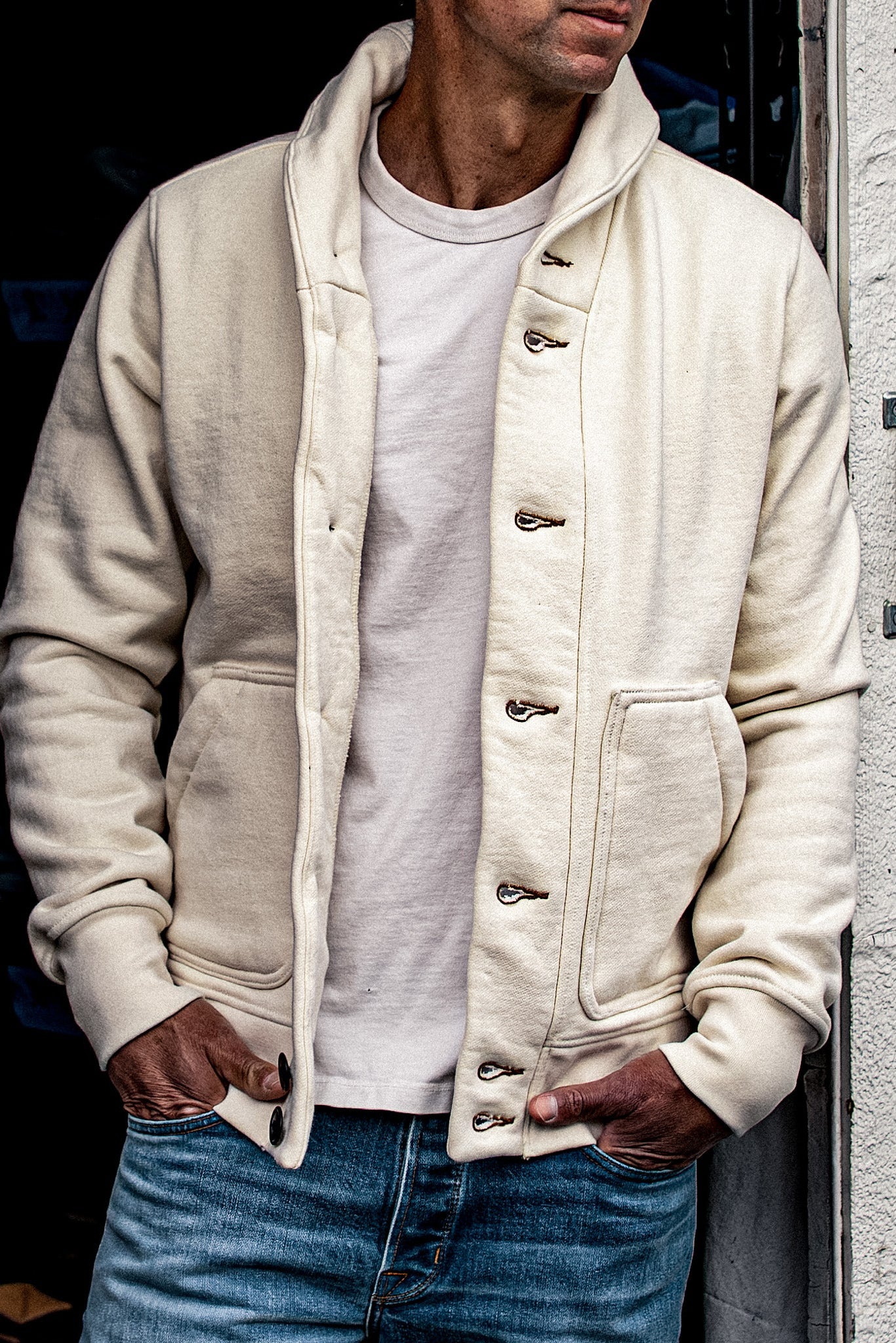 Natural cotton French terry shawl collar cardigan worn open over a white tee with blue jeans.
