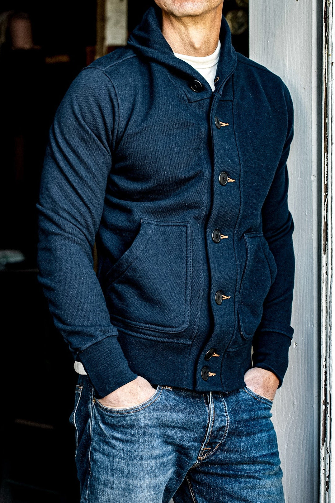 Navy shawl collar French terry cardigan worn over a cream tee with selvedge denim jeans.