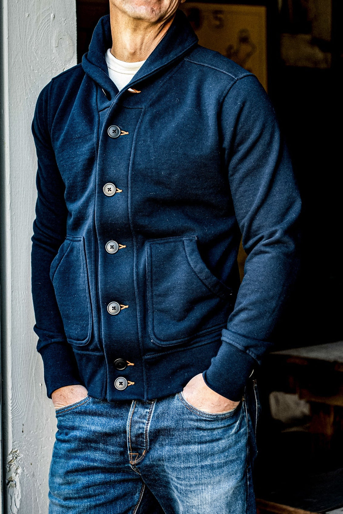 Navy shawl collar French terry cardigan worn over a white tee with faded blue jeans.